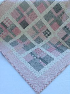 a pink and grey quilt on a white table