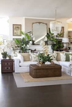 a living room filled with white furniture and lots of greenery on top of it