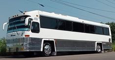 a white bus is parked on the side of the road in front of power lines