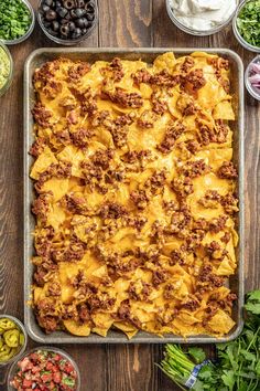 a casserole dish filled with ground beef, cheese and other toppings on a wooden table