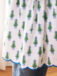 a person wearing a white shirt with green trees on it and blue trimmings