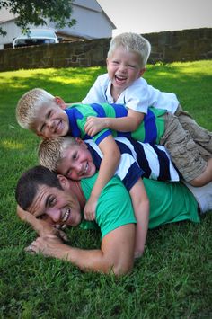 a group of young men sitting on top of each other in the grass