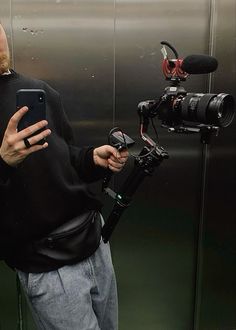 a man standing in front of a camera holding a cell phone