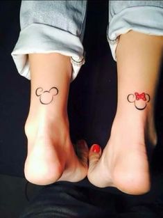 two people with matching mickey mouse tattoos on their feet, one has a red bow