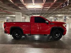 a red truck parked in a parking garage with black rims on it's tires