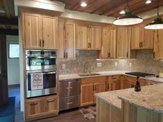 a large kitchen with wooden cabinets and stainless steel appliances in the center, along with marble counter tops