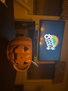 an orange helmet hanging from the ceiling in front of a television screen with a logo on it