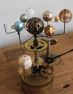 a small clock with different types of planets on it's face and gears in the middle