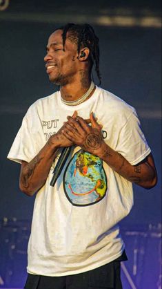 a man with dreadlocks standing in front of a microphone and wearing a white shirt