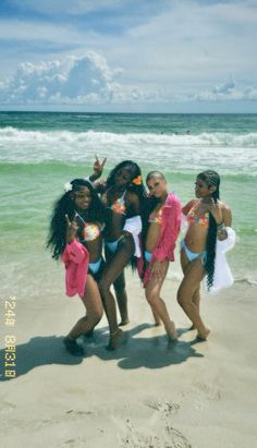 four women in bathing suits standing on the beach