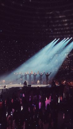 a group of people standing on top of a stage with their arms in the air