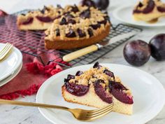 a slice of plum pie on a plate with a fork next to it and two other desserts in the background