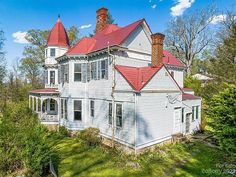 an old white house with red roof and chimneys