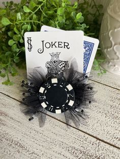 the joker playing card brooch is sitting on top of a table next to some plants