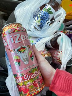 a person holding a pink drink in their left hand and plastic bags on the ground