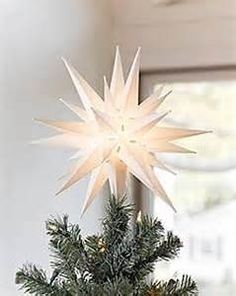 a white star decoration on top of a christmas tree