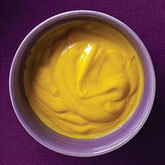 a white bowl filled with yellow liquid on top of a purple table