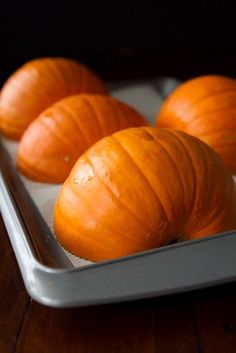 three peeled pumpkins in a metal pan on a wooden table