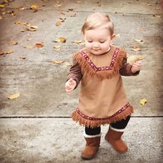 a toddler is standing on the sidewalk and smiling