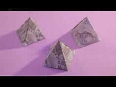 three origami pyramids sitting on top of a purple surface