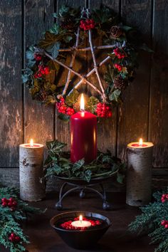 a candle and some holly wreaths on a table