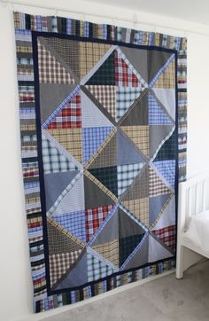 a quilt hanging on the wall next to a bed