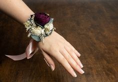 a woman's hand wearing a purple wrist corsage