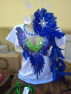 a white shirt with blue and green feathers on the chest, next to other items