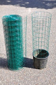 two green wire baskets sitting next to each other on the ground near a potted plant