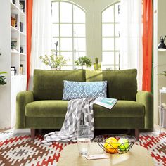 a living room with a green couch and orange curtains