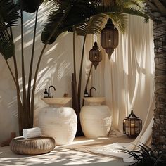 two white vases sitting next to each other on a floor under a palm tree