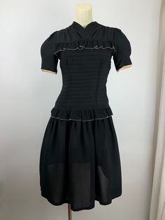 Cute 1940'S black rayon dress with a fitted bodice and a drop waist. There is this pleated flouncy trim that lines the chest and wraps around the drop waist. There is an attached belt that ties in the back. Super sweet. The sleeves are short and puffy. There is a metal talon side zipper as well as 4 cloth covered buttons in back along the neckline. The skirt is rather short and flirty, which reminds me of cute baby doll dresses. This dress is in EXCELLENT VINTAGE CONDITION... no real issues to p Black Dress With Fitted Bodice For Vintage Events, Fitted Black Dress For Vintage Events, Black Fitted Dress For Vintage Events, 1950s Style Black Dress For Vintage Events, Fitted Vintage Dress With Ruffles For Formal Occasions, Fitted Black Dress In 1950s Style, Black Fitted 1950s Style Dress, 1950s Black Vintage Dress, Fitted Black Dress 1950s Style