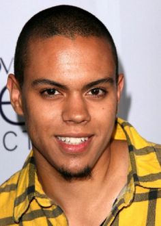 a close up of a person wearing a yellow and black checkered shirt with a smile on his face