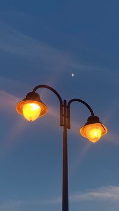 two street lights with the moon in the background