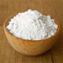 a wooden bowl filled with white powder on top of a table