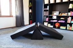 an upside down black sculpture in the middle of a room with bookshelves and toys