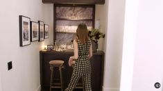 a woman is standing in front of a bar and looking at the wall with pictures on it