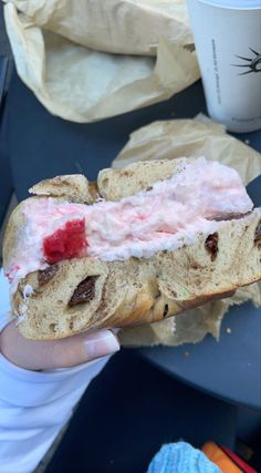 a person holding a sandwich with cream cheese and fruit on it