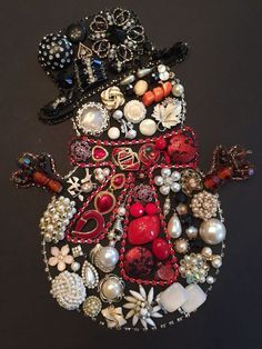 a snowman ornament made out of beads and other items on a black surface