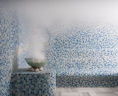 a bowl with steam rising out of it sitting on top of a counter next to a tiled wall