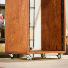 a wooden cabinet sitting on top of a hard wood floor next to a metal shelf