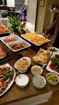 a table filled with lots of different types of pizzas and other foods on trays