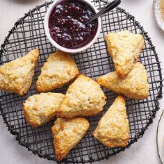 scones on a wire rack with jam in a bowl next to other pastries