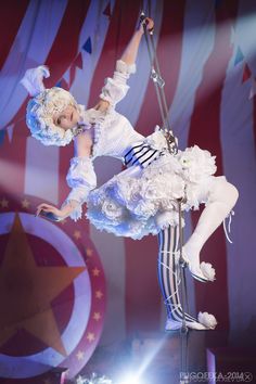 a woman dressed in white performing on stage with an american flag behind her and lights