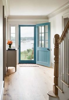 a blue front door is open on the inside of a house with white walls and wood floors