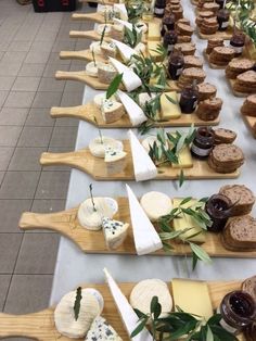 a long table topped with lots of cheeses and crackers on wooden paddles