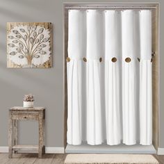 a white shower curtain in a bathroom next to a wooden table