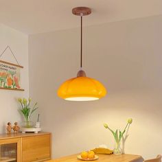 a dining room table with two chairs and a yellow light hanging over it