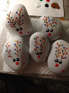 painted rocks with reindeer faces on them sitting on a towel next to a piece of paper