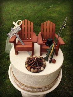 two wooden chairs sitting on top of a white cake covered in rocks and gravel next to an umbrella